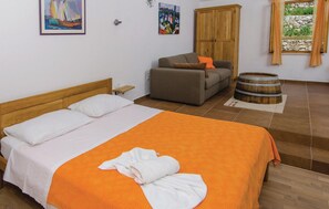 Ein Schlafzimmer mit einem Bett, einer Couch, einem Holzschrank und einem Fass.