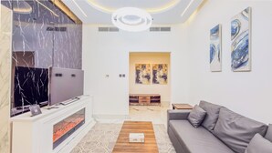 A modern living room with a fireplace, a sofa, and artwork on the walls. - Escan Tower- Dubai Marina (Dubai)