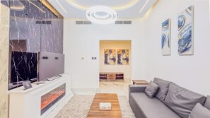A modern living room with a fireplace, a sofa, and artwork on the walls. - Escan Tower- Dubai Marina (Dubai)