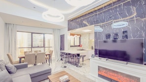 A modern living room with a flat-screen TV, a fireplace, and a dining area with a view of the cityscape. - Escan Tower- Dubai Marina (Dubai)