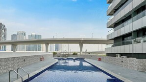 A rooftop swimming pool with a cityscape view, a covered walkway, and a modern building structure. - Escan Tower- Dubai Marina (Dubai)