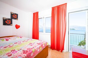 Ein Schlafzimmer mit Bett, Fenster und einem Balkon mit Meerblick.