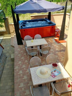 Eine Terrasse im Freien mit Whirlpool, Tischen und Stühlen.