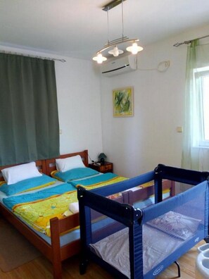 Ein Zimmer mit zwei Betten, einer Deckenleuchte, einem Bild an der Wand und einem Fenster mit Vorhängen.
