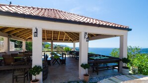 An outdoor patio with tables and chairs, a pergola structure, and a view of the sea. - Apartment With sea View in Orasac (Dubrovnik)