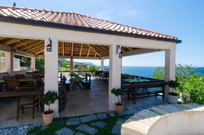 An outdoor patio with tables and chairs, a pergola structure, and a view of the sea. - Apartment With sea View in Orasac (Dubrovnik)