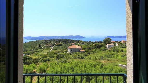 A balcony with a view of a coastal landscape, including houses and greenery. - Apartment With sea View in Orasac (Dubrovnik)