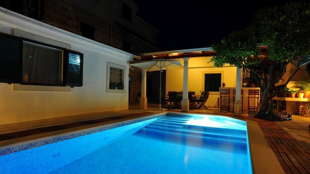 A swimming pool with a tiled edge, a covered patio area with outdoor furniture, and a building with windows and shutters. - Villa Anni-two Bedroom Apartment With Terrace (Sutivan)
