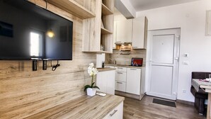 A modern kitchen with wooden cabinetry, a built-in TV, and a small orchid plant. - Apartments Victoria - One Bedroom Apartment With Terrace and Sea View (Pakostane)