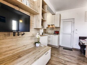 Eine moderne Küche mit Holzschränken, einem integrierten Fernseher und einer kleinen Orchidee.