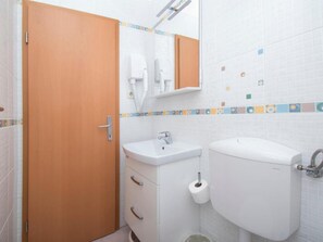 A bathroom with a toilet, sink, and a wooden door. - Apartments Antonio - One Bedroom Apartment With Balcony - 1 (Tucepi)