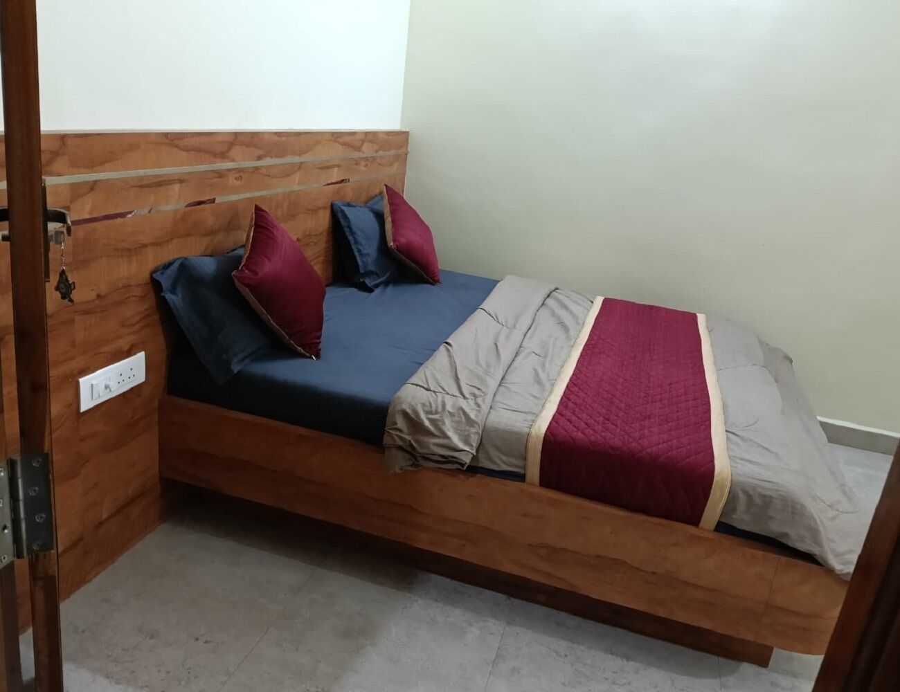 Una cama individual con cabecera de madera, colchón azul y varias almohadas.
