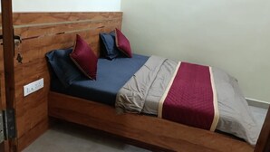 Un letto singolo con una testiera in legno, un materasso blu e diversi cuscini.