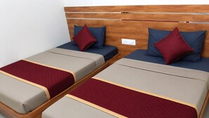 Due letti singoli con testiere in legno, ciascuno con un materasso, una coperta trapuntata rossa e un cuscino.