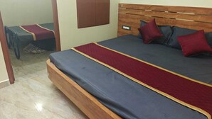 Un letto matrimoniale con testiera in legno, una coperta a righe rosse e blu e due cuscini.