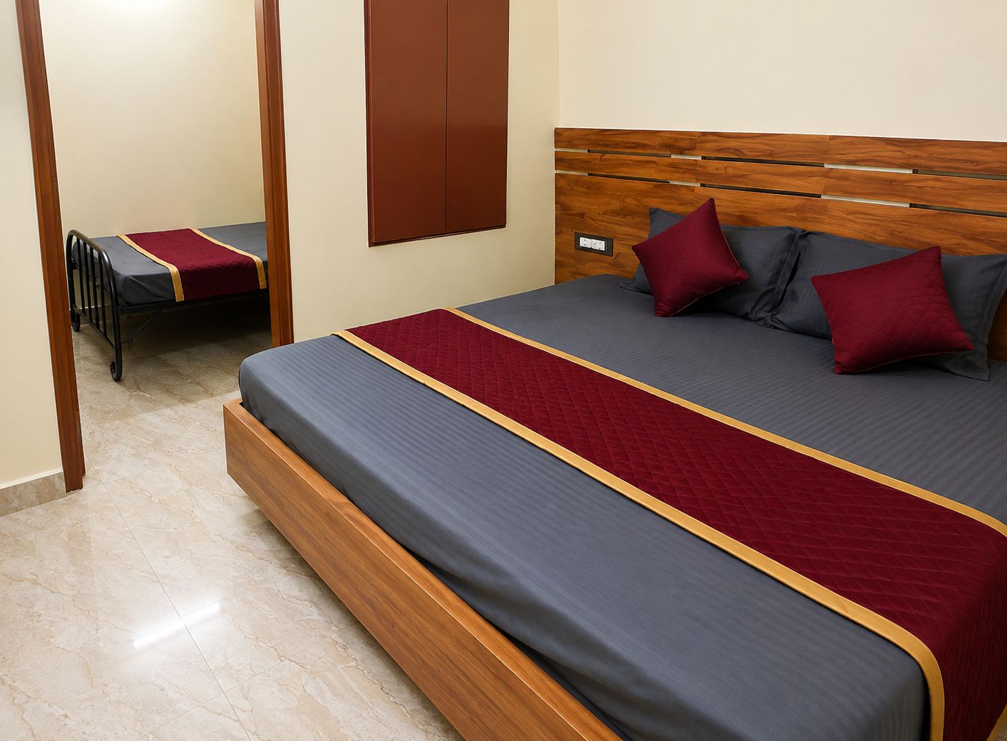 A hotel room with a large bed, a wooden headboard, and a small desk with a chair.