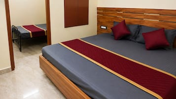 A hotel room with a large bed, a wooden headboard, and a small desk with a chair.