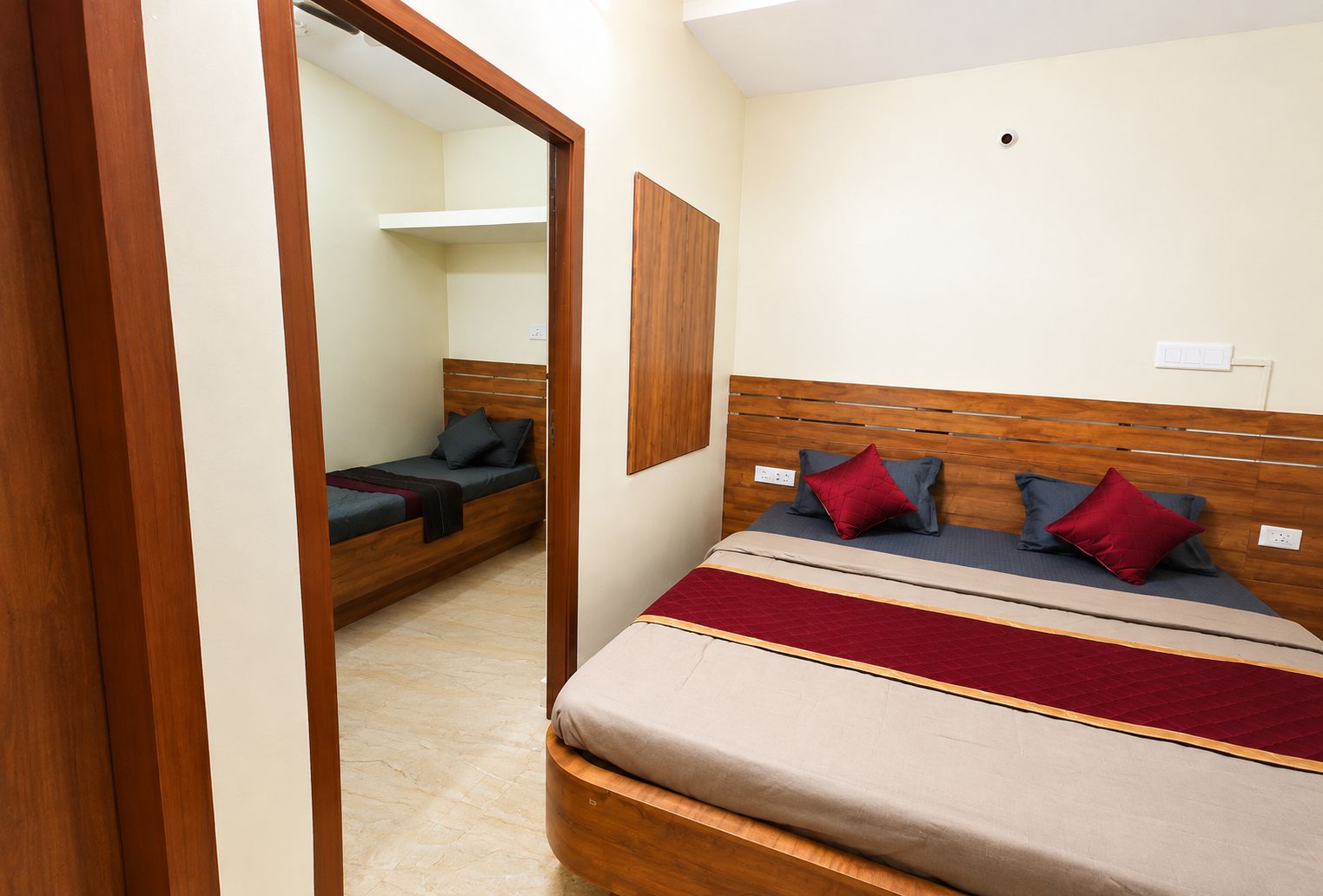 A bedroom with a large bed, a smaller bed, and a mirror.