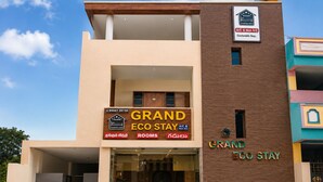 Un edificio a due piani con un cartello che indica 'Grand Eco Stay', con camere dotate e non dotate di aria condizionata.
