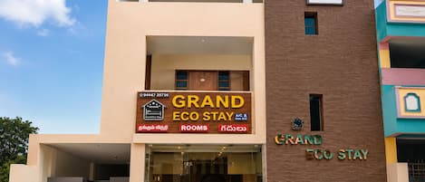 A two-story building with a sign for 'Grand Eco Stay' indicating A/C and Non A/C rooms.