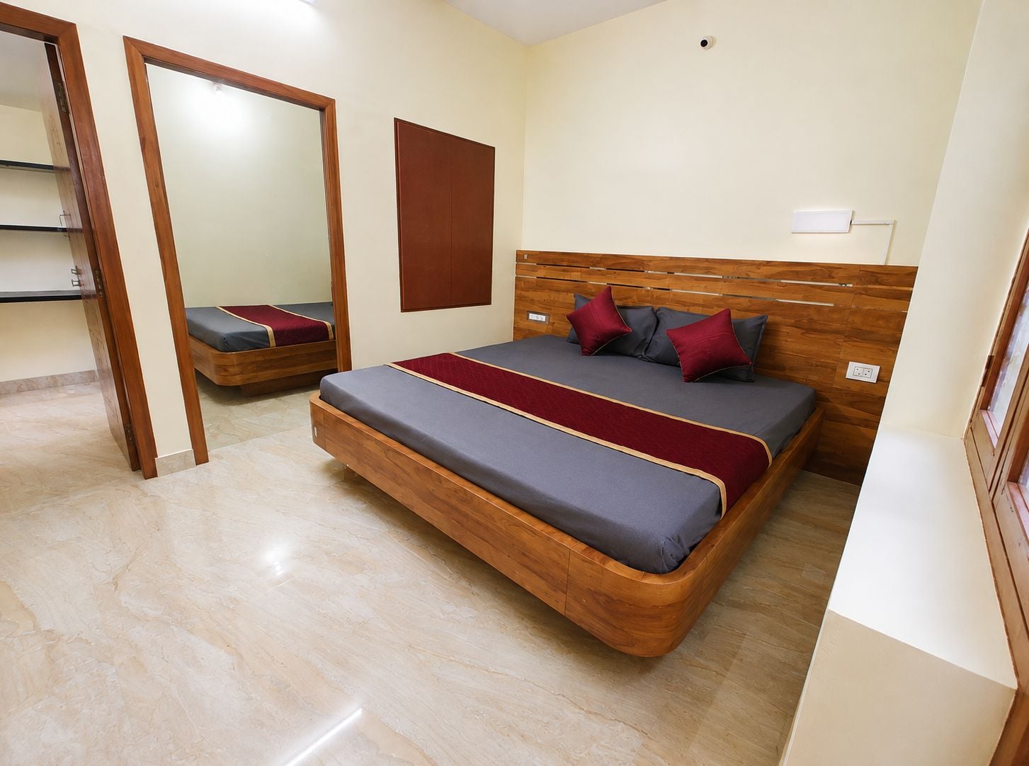 Un dormitorio con cama, cabecera de madera, espejo y lámpara de pared.