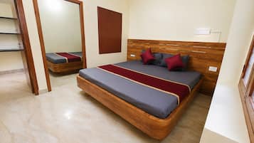 Un dormitorio con cama, cabecera de madera, espejo y lámpara de pared.