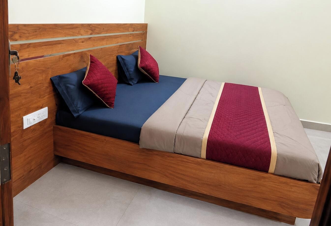 A single bed with a wooden headboard, a blue mattress, and two pillows.