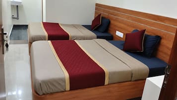 A hotel room with two beds, each with a wooden headboard, and a small bedside table.