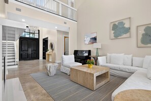A spacious living room with a piano, a coffee table, and a sofa. - Private Pool + Hot Tub + Boat Dock | 2-Min Walk to Beach | Beach Drive Estate (Delray Beach)