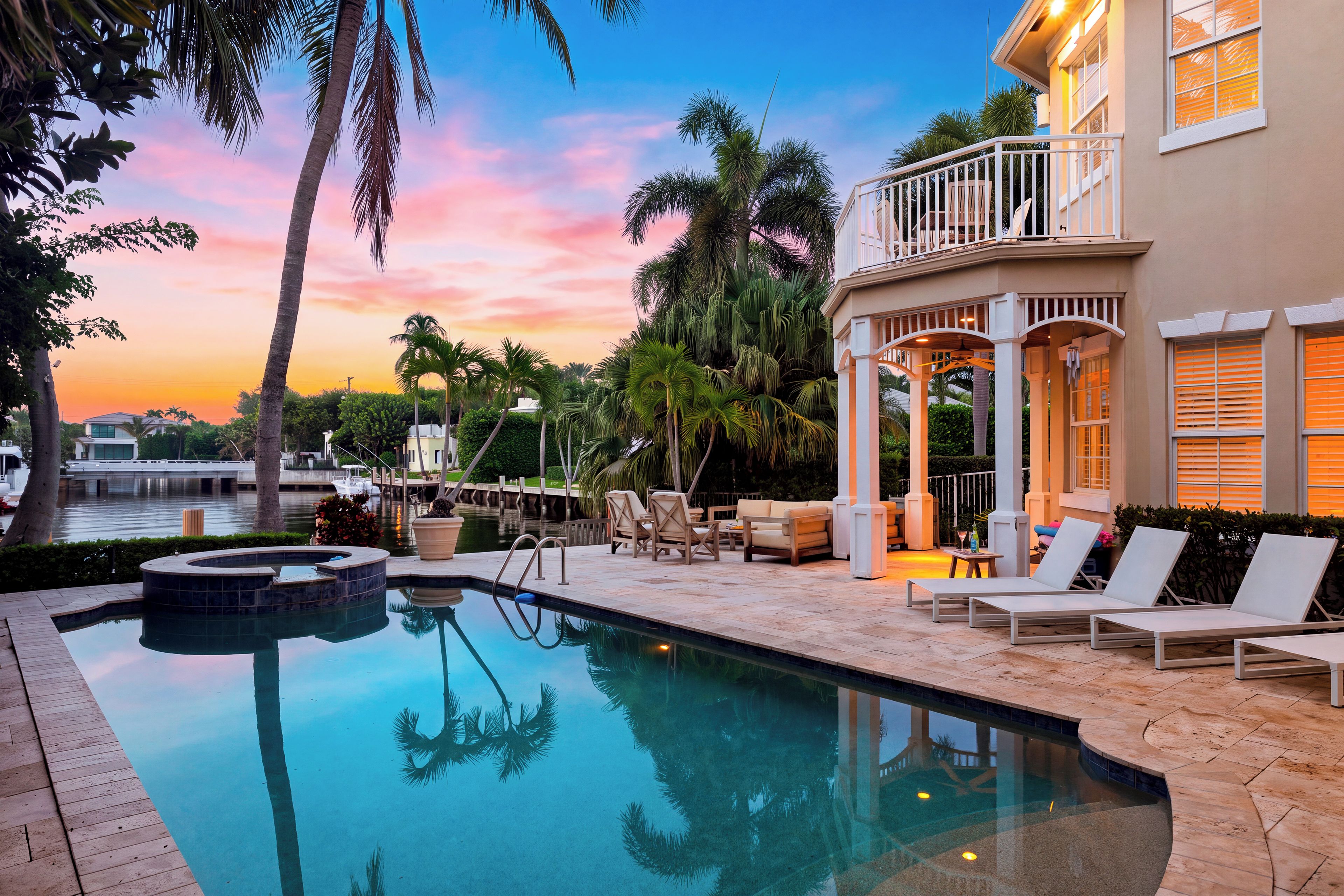 A pool area with lounge chairs, a hot tub, and a view of the water.