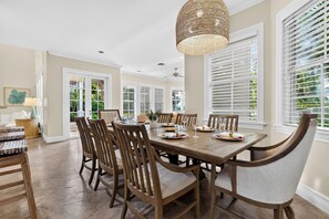 A dining area with a wooden table set for six, surrounded by chairs, with a ceiling fan and pendant light above. - Private Pool + Hot Tub + Boat Dock | 2-Min Walk to Beach | Beach Drive Estate (Delray Beach)