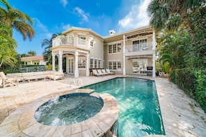 A large house with a swimming pool, outdoor seating, and a hot tub.