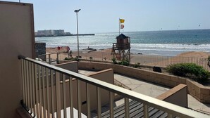 A balcony with a view of the beach, a lifeguard tower, and a clear sky. - Vacation Home 'Casa Médano 12' with Sea View, Private Terrace and Wi-Fi (El Médano)