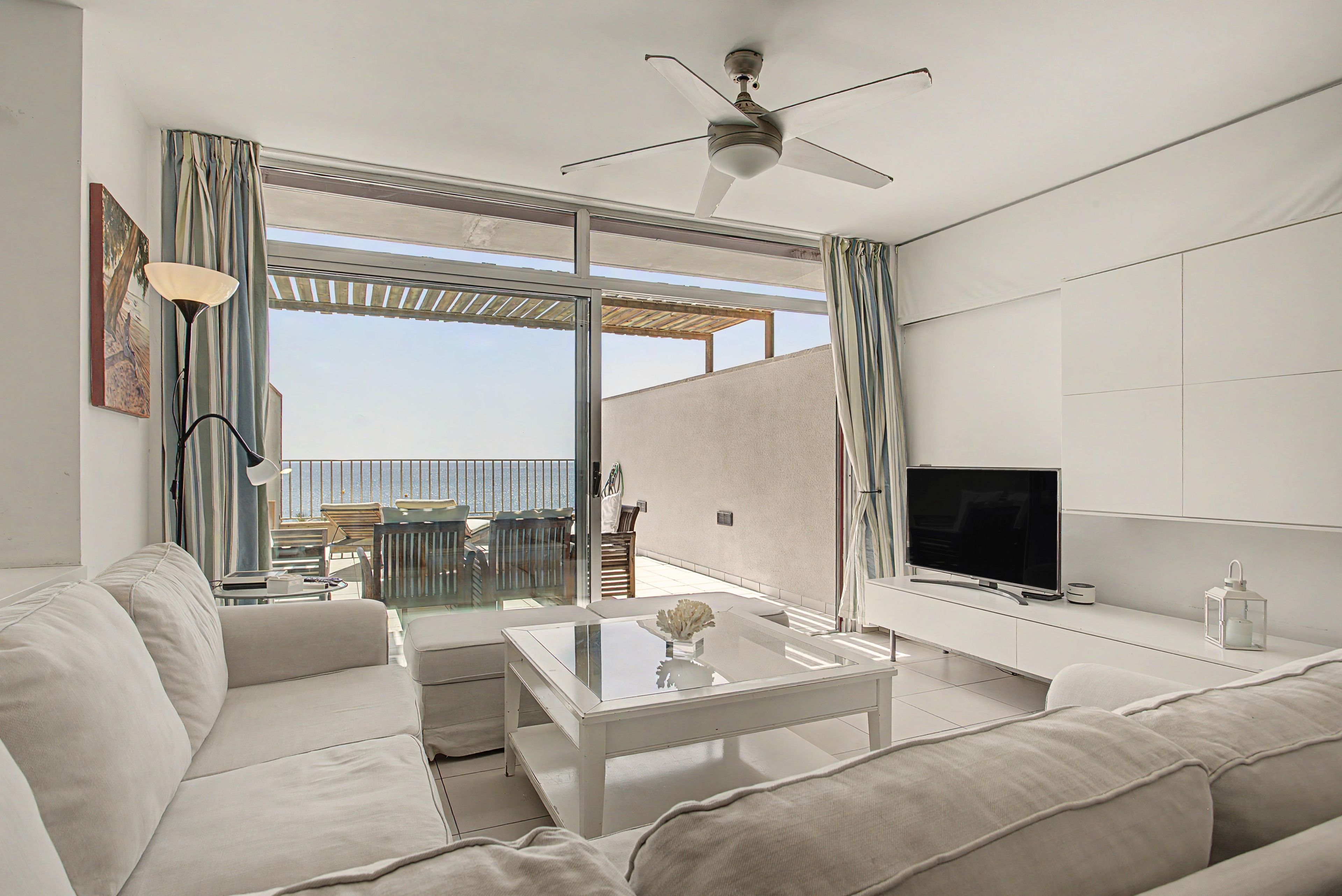 Una sala de estar moderna con un sofá, una mesa de centro, un televisor y un balcón con vistas.