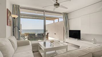 Una sala de estar moderna con un sofá, una mesa de centro, un televisor y un balcón con vistas.
