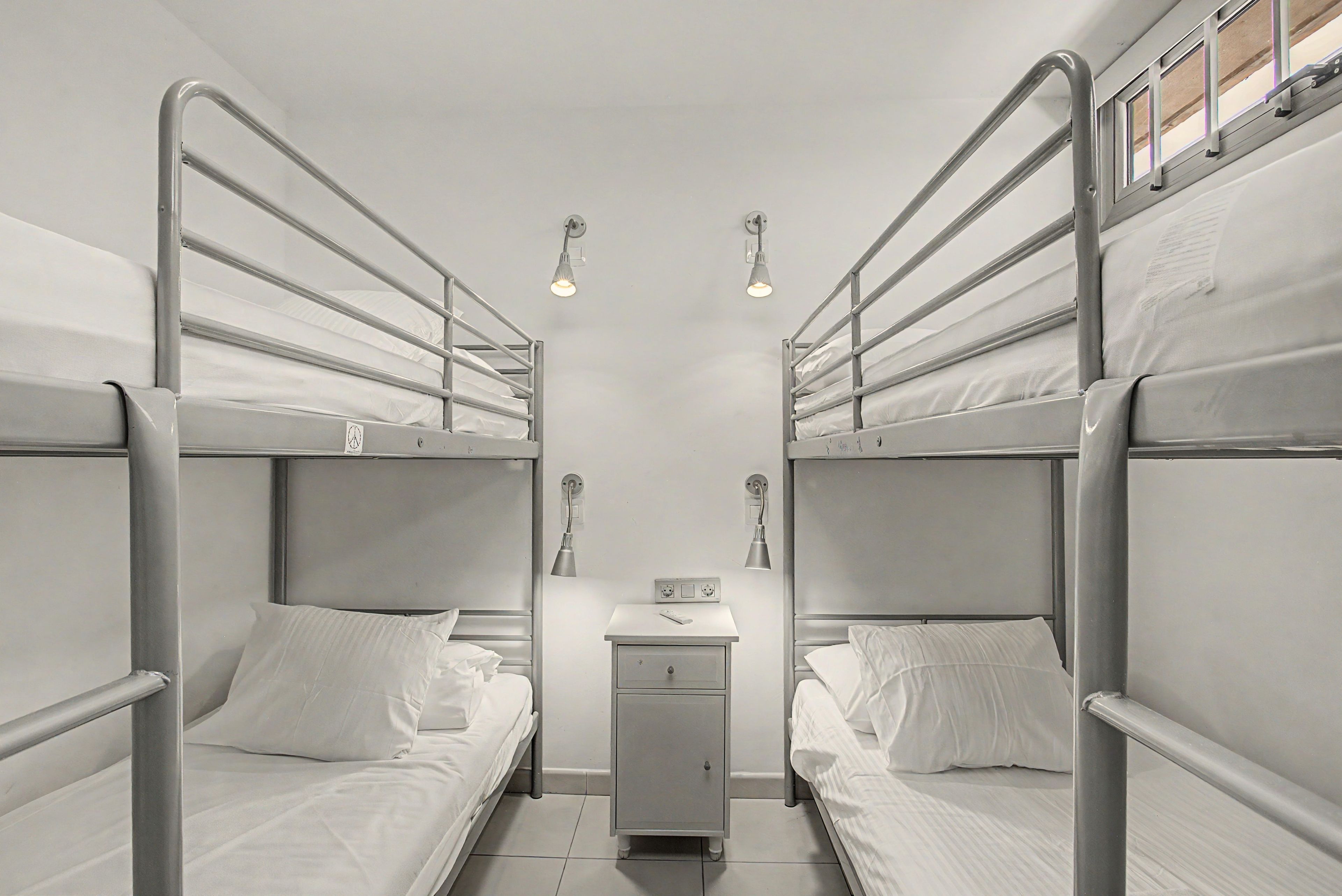 Een slaapkamer met een stapelbed, een klein bureau en twee wandlampen.