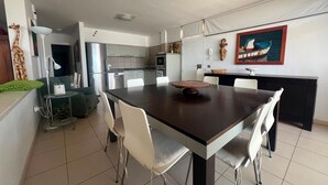 A modern kitchen with a dining area, including a table with chairs, a ceiling fan, and a refrigerator. - Vacation Home 'Casa Médano 12' with Sea View, Private Terrace and Wi-Fi (El Médano)
