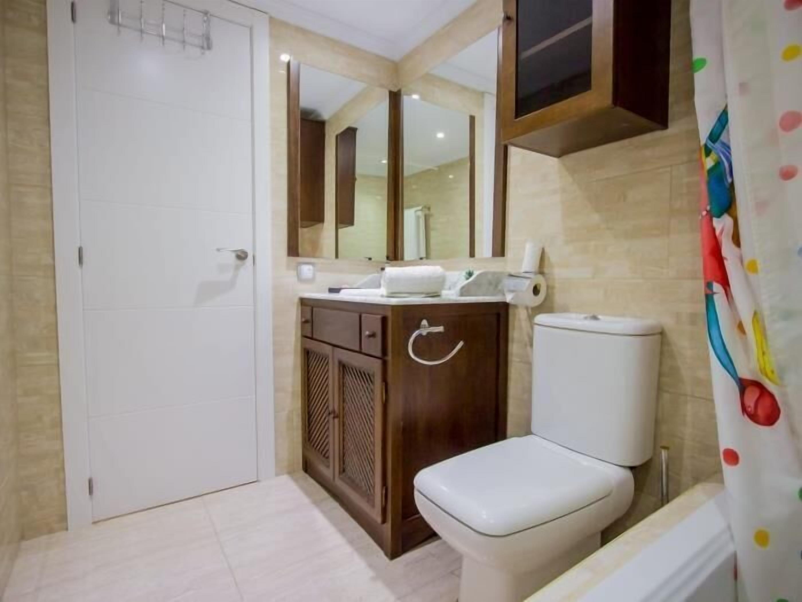 A bathroom with a toilet, sink, mirror, and a shower curtain.