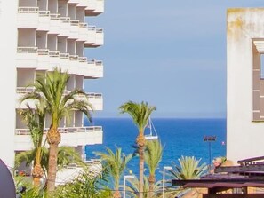 A hotel with a view of the sea, palm trees, and a building with balconies. - Sunstay Flat Torresol (Torremolinos)