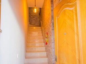 A staircase with a light fixture, a wooden door, and a wall with a textured pattern. - Sunstay Flat Torresol (Torremolinos)