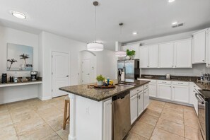 A modern kitchen with white cabinets, granite countertops, and stainless steel appliances. - Screened Pool + Hot Tub + Game Room | Gated Resort Near Parks | Palm & Play (Kissimmee)