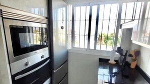 Una cucina con forno a incasso, una finestra con sbarre e un piano di lavoro con utensili da cucina.