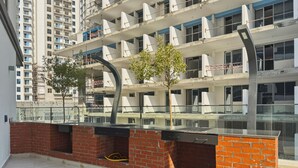 A multi-story residential building with balconies, a brick wall, and a glass railing. - Bloomfields Studio in NAS3 - Arjan Dubai (Dubai)