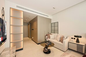 A modern living room with a sofa, coffee table, and a flat-screen TV. - Bloomfields Studio in NAS3 - Arjan Dubai (Dubai)