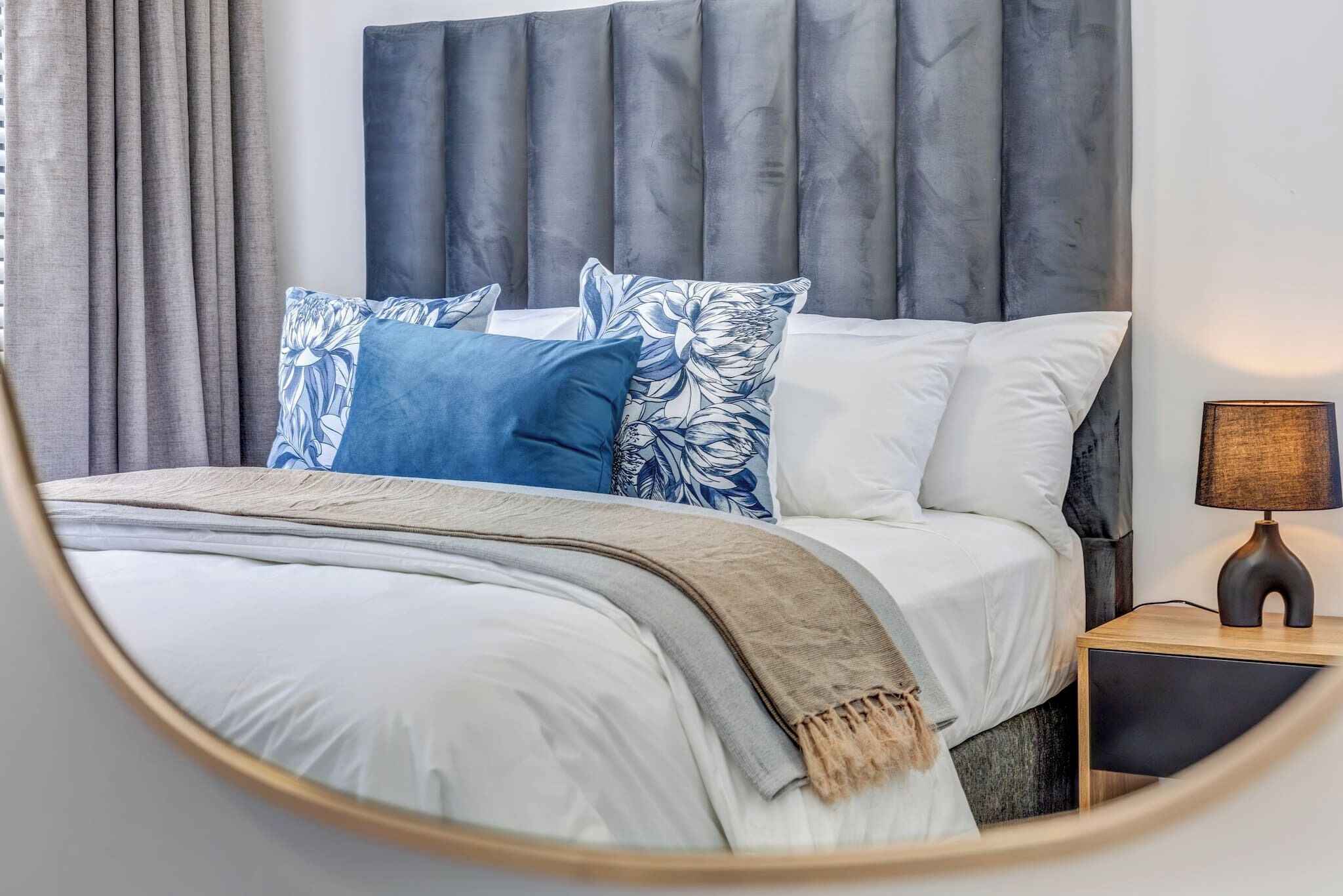 A bed with a headboard, pillows, and a bedside table with a lamp.
