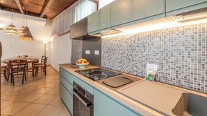 Una cocina moderna con horno empotrado, un lavamanos y un comedor con mesa y sillas.