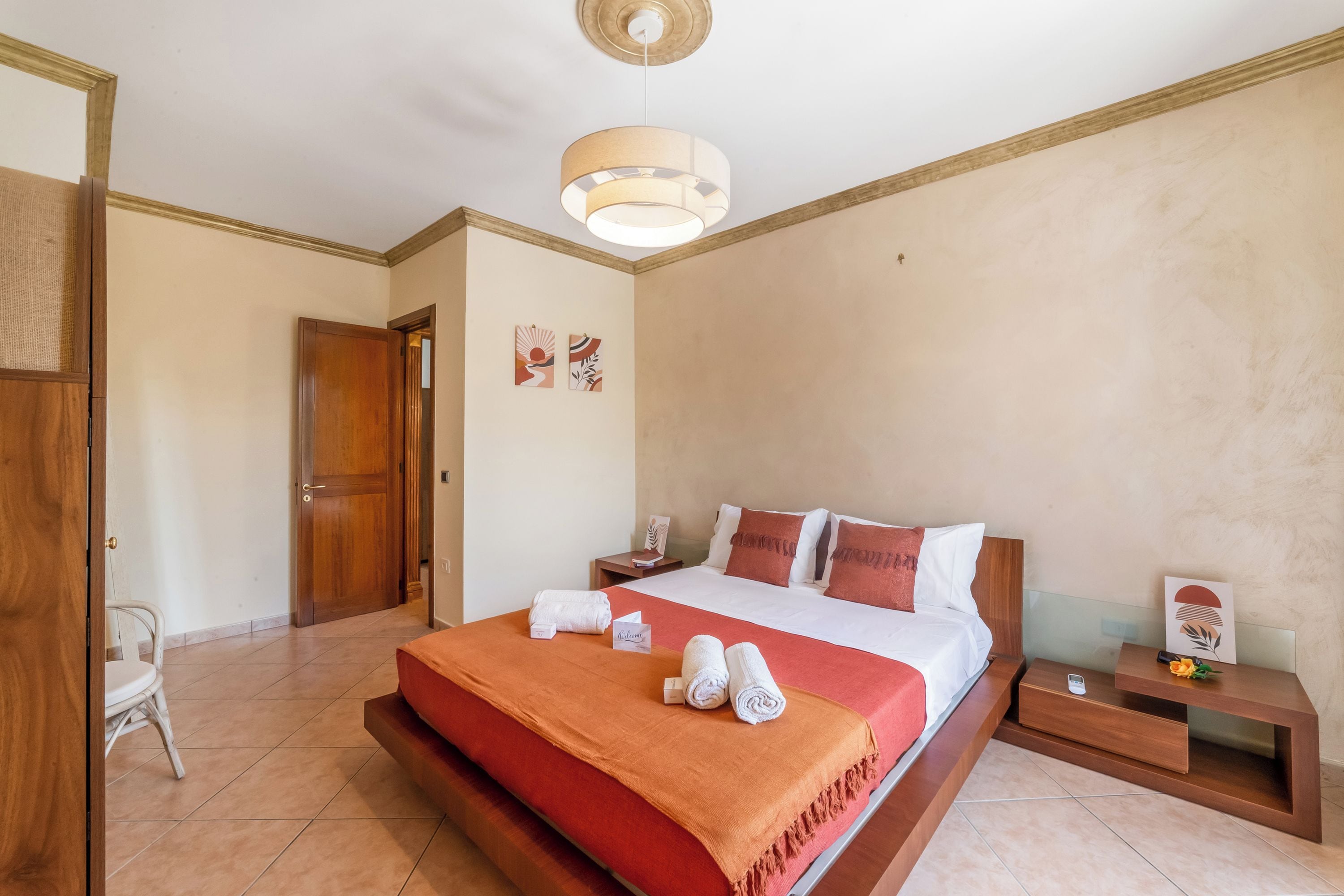 A hotel room with a bed, a nightstand, a chair, and a door.