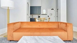 A modern living room with a sofa, a coffee table, and a lamp. - The Harlequin by AvantStay | Sleeps 12, 3 Suites | Steps to French Quarter (New Orleans)