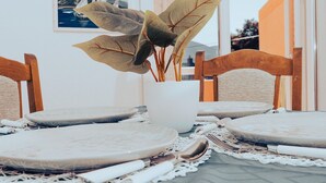A dining table with a white vase containing a plant, surrounded by wooden chairs and a white table runner. - Hvar spa & Apartments-superior 1 Bedroom Apartment (Jelsa)