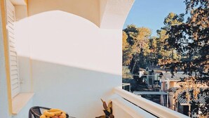 A balcony with a table, chairs, a potted plant, and a view of trees and houses. - Hvar spa & Apartments-superior 1 Bedroom Apartment (Jelsa)